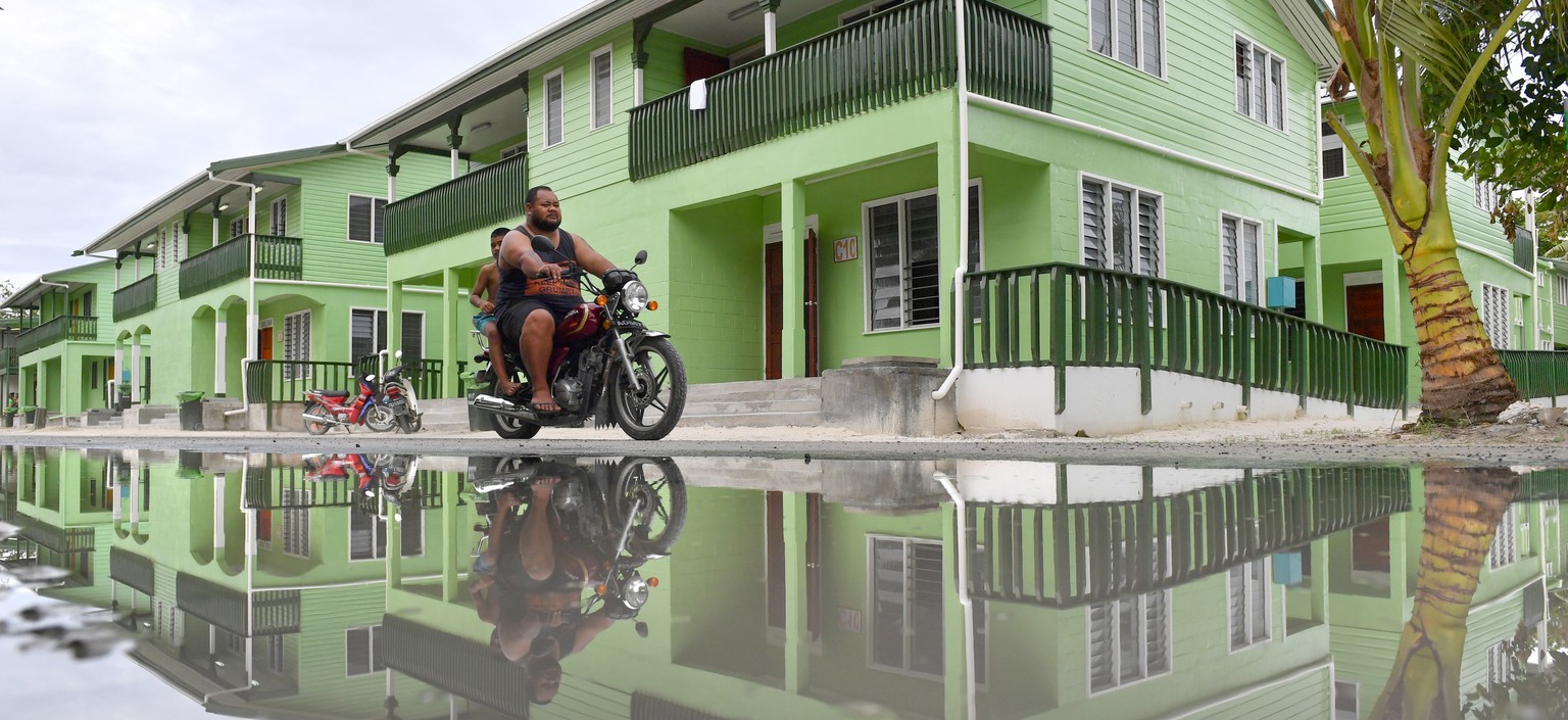 epa07770648 A man riding a motorbike is seen reflected in a puddle of water in Funafuti, Tuvalu, 13 August 2019. The 50th Pacific Islands Forum and Related Meetings, fostering cooperation between gove ...