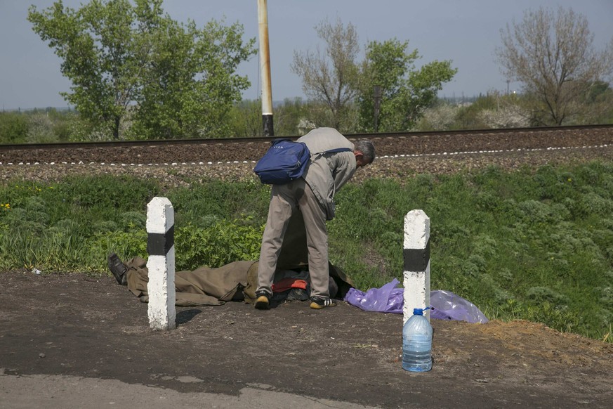 Ein Mann beugt sich über eine Leiche. Nach Angaben der Regierung hatten Aufständische in Slowjansk zwei Hubschrauber abgeschossen, zwei Soldaten starben. Auch unter den Rebellen gab es Tote.