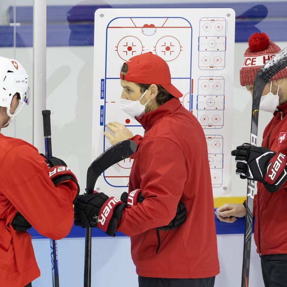 Patrick Fischer, center, head coach of Switzerland national ice hockey team, talks to his player forward Enzo Corvi, left, past Christian Wohlwend, right, assistant coach, during a training of the Swi ...