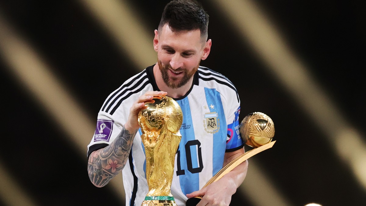 epaselect epa10373265 Lionel Messi of Argentina touches the World Cup trophy as he passes it after winning the golden ball award during the awards ceremony after the FIFA World Cup 2022 Final between  ...