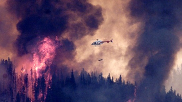 A helicopter flies past the northeast corner of the Lost Creek fire in an effort to control the blaze south of Blairmore, Alberta Canada Tuesday July 29, 2003. Light winds were blowing a raging wildfi ...