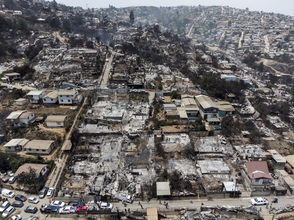 Locals clean the rubble of burnt-out houses after forest fires reached their neighborhood in Vina del Mar, Chile, Sunday, Feb. 4, 2024. (AP Photo/Cristobal Basaure)