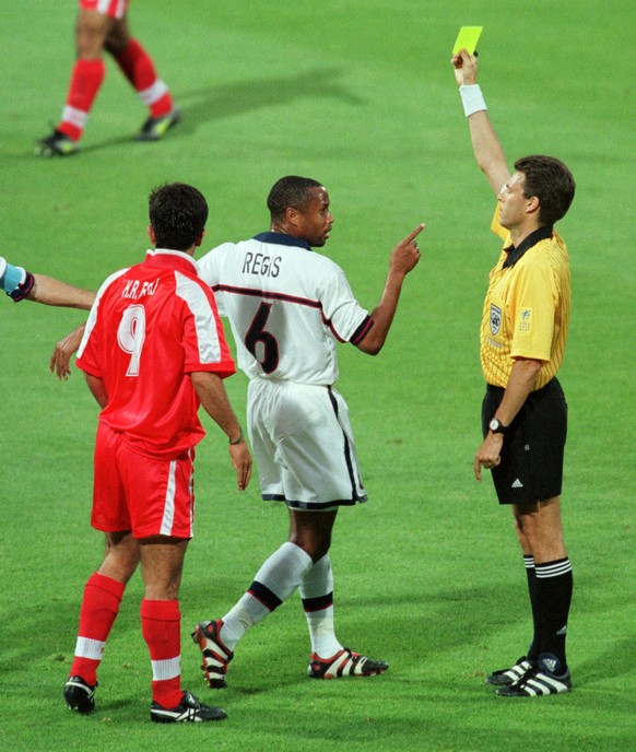 Referee Urs Meier of Switzerland shows the yellow card to US David Regis (6) as Iran's Hamid Estili looks on during , Sunday, June 21, 1998, Iran vs USA Group F World Cup match at Gerland Stadium ...