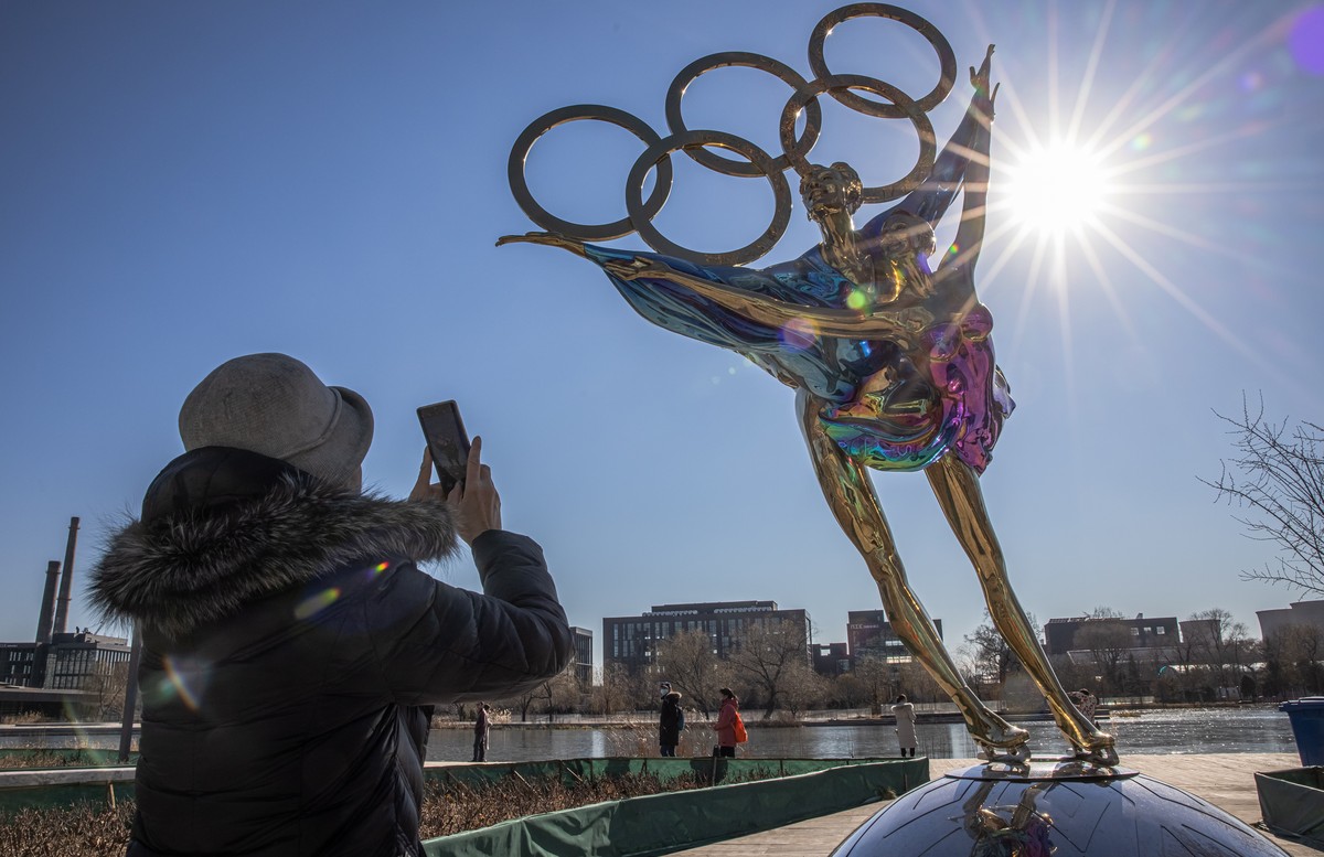 epaselect epa09614026 A woman takes photos with her mobile phone of a figure skating sculpture erected for the Beijing 2022 Winter Olympics, at the Shougang Industrial Park, which will be used as a ve ...