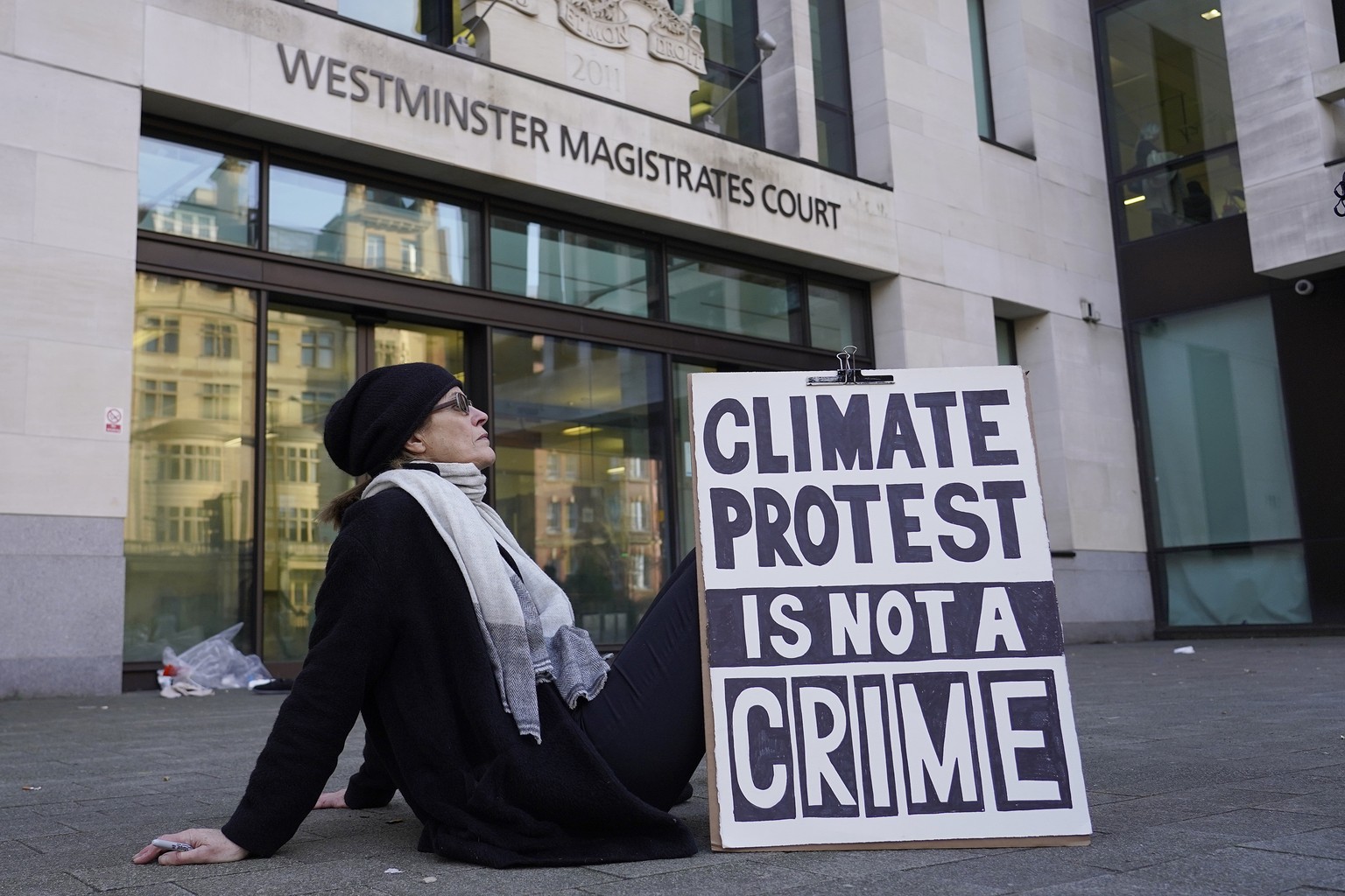 A protester sits outside Westminster Magistrates Court in London, Thursday, Feb. 1, 2024. Climate activist Greta Thunberg is on trial for protesting outside a major oil and gas industry conference in  ...