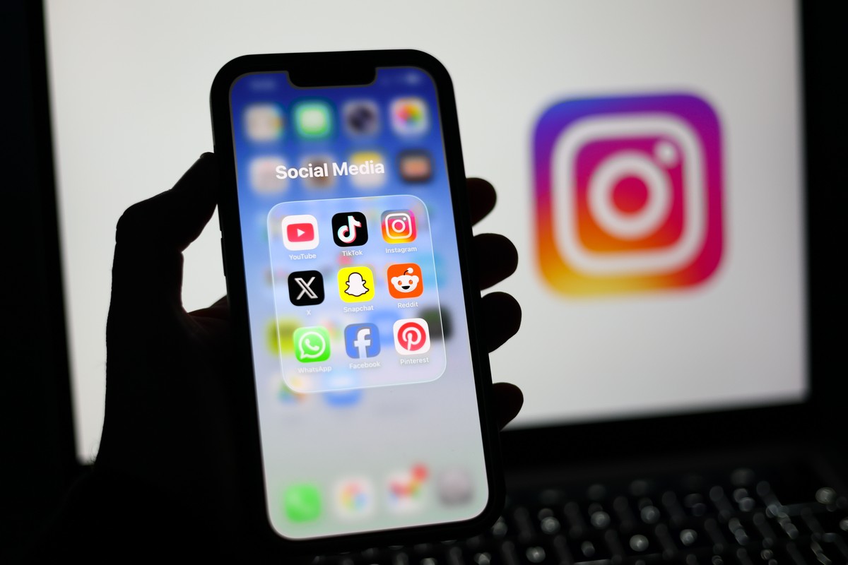 epa12674741 Social media applications displayed on a mobile phone alongside the Instagram logo displayed on a laptop screen in Liverpool, Britain, 23 January 2026. A proposal to ban under-16s from acc ...