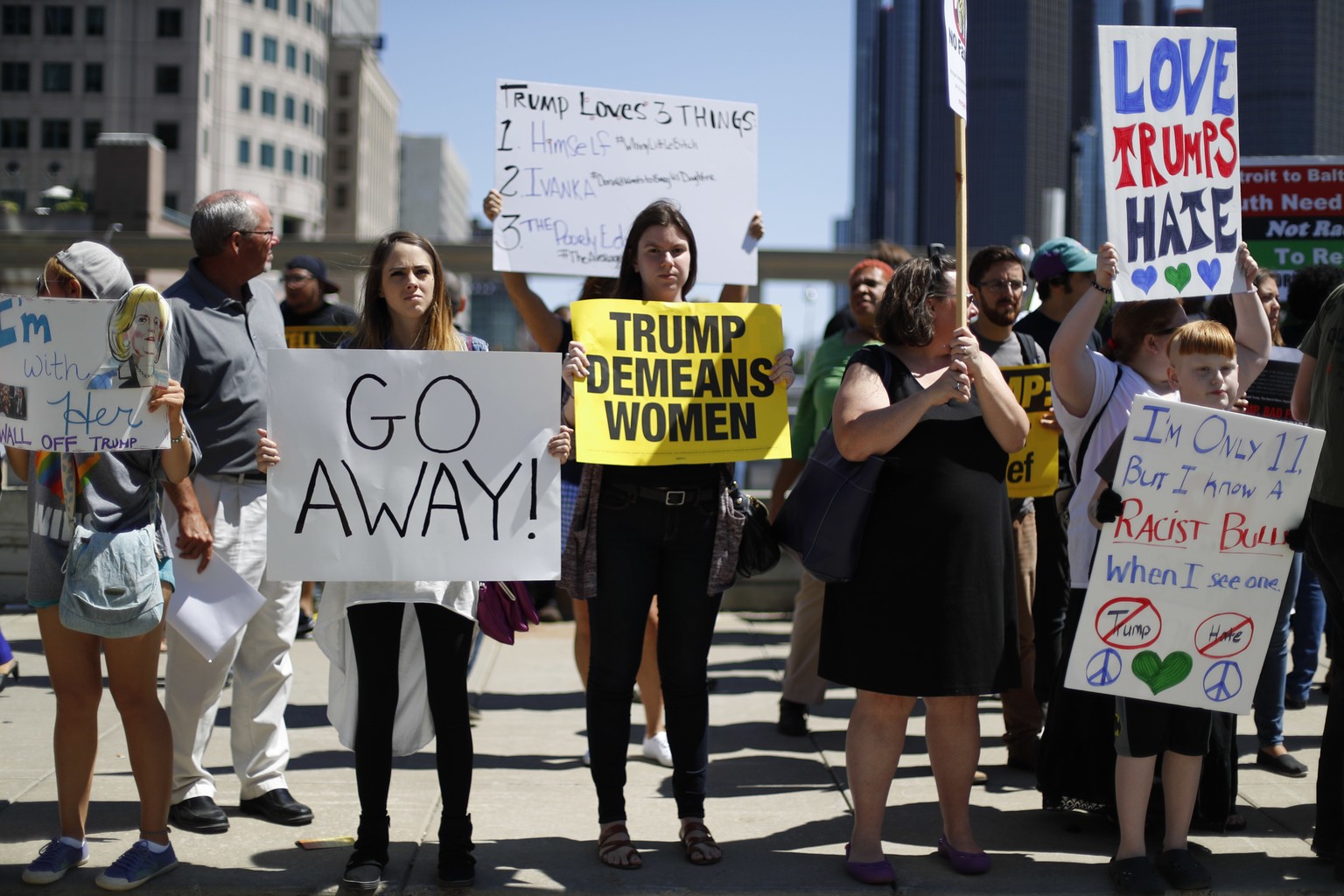 Demonstrators hold signs while Republican presidential candidate Donald Trump delivered an economic policy speech to the Detroit Economic Club in Detroit, Monday, Aug. 8, 2016. (AP Photo/Paul Sancya)