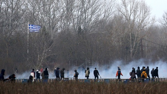 epa08268550 Migrants run from tear gas employed by Greek police officers as they attempt to cross the closed-off Turkish-Greek border in a bid to reach European soil, in Edirne, Turkey, 04 March 2020. ...