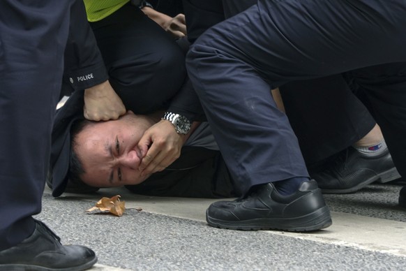 In this photo taken on Sunday, Nov. 27, 2022, policemen pin down and arrest a protester during a protest on a street in Shanghai, China. Authorities eased anti-virus rules in scattered areas but affir ...