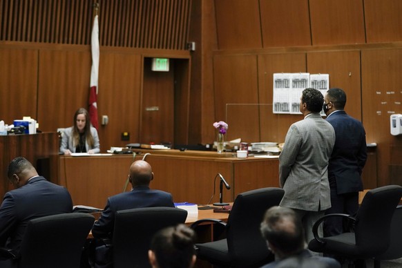 Eric Holder Jr., right, who is accused of killing rapper Nipsey Hussle, and his attorney, Aaron Jansen, listen as court clerk Sarah Girardot reads the verdict in a courtroom in Los Angeles, Wednesday, ...