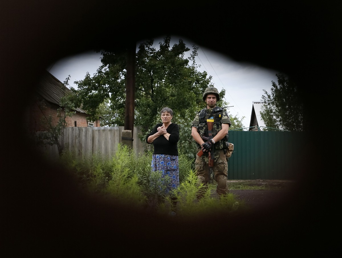 Ein Polizist steht bei einer Einheimischen, während ihr Haus durchsucht wird.
