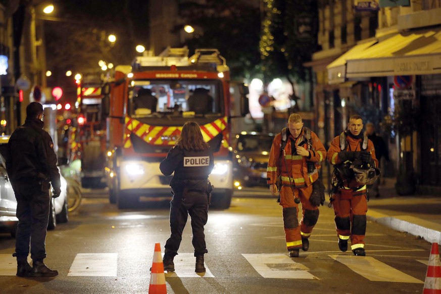 Firefighters and policemen stand on the scene of a fire in Paris, Tuesday, Feb. 5, 2019. A fire in a Paris apartment building early Tuesday killed seven people and sent residents fleeing to the roof o ...