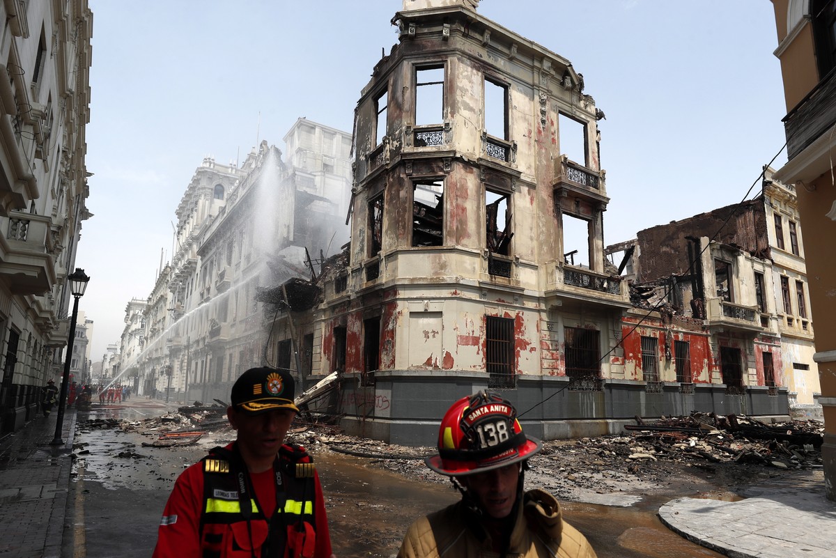 epa10418823 Firefighters work outside an old house devastated by fire during protests in downtown Lima, Peru, 20 January 2023. Firefighters are still working at the area of the house that was declared ...