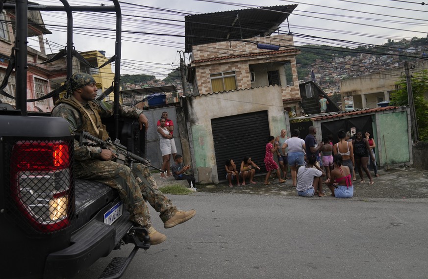 A special forces military police officer rides past residents during an operation against alleged drug traffickers in the Vila Cruzeiro favela of Rio de Janeiro, Brazil, Friday, Feb. 11, 2022. (AP Pho ...