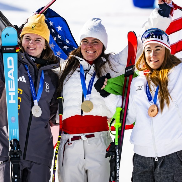 Silver medalist Emma Aicher, left, Gold medalist Breezy Johnson of the United States, center, and Bronze medalist Sofia Goggia of Italy, right, celebrate after the medals ceremony of the women's  ...