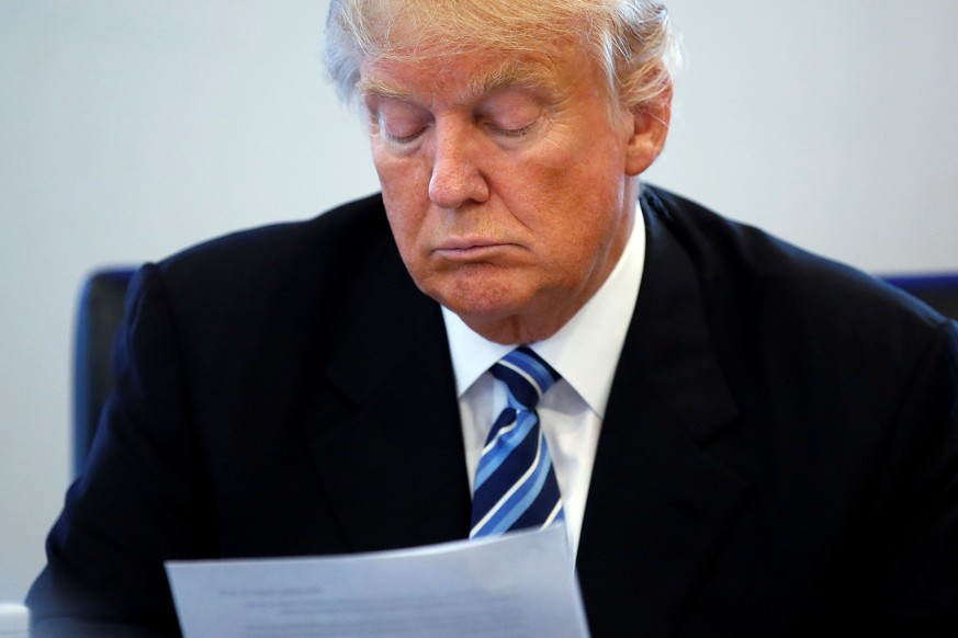 Republican presidential nominee Donald Trump reads a document during a round table discussion on security at Trump Tower in the Manhattan borough of New York, U.S., August 17, 2016. REUTERS/Carlo Alle ...