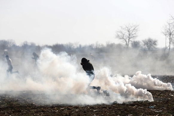 Migrants run to avoid tear gas thrown by Greek police during clashes near the Pazarkule border gate in Edirne, at the Turkish-Greek border on Monday, March 2, 2020. Thousands of migrants and refugees  ...