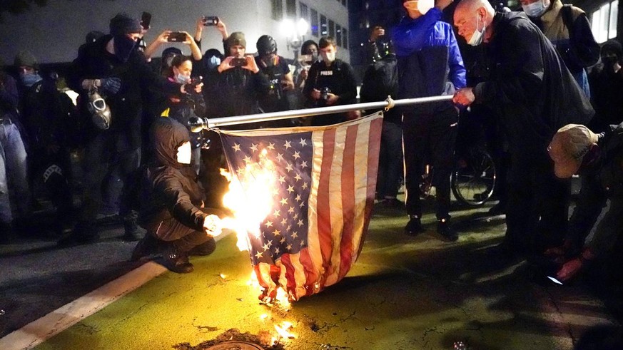 A protester lights an American flag on fire during a demonstration Wednesday, Nov. 4, 2020, in Portland, Ore. (AP Photo/Marcio Jose Sanchez)