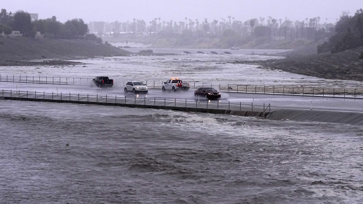 Vehicles cross over a flood control basin that has almost reached the street, Sunday, Aug. 20, 2023, in Palm Desert, Calif. Forecasters said Tropical Storm Hilary was the first tropical storm to hit S ...