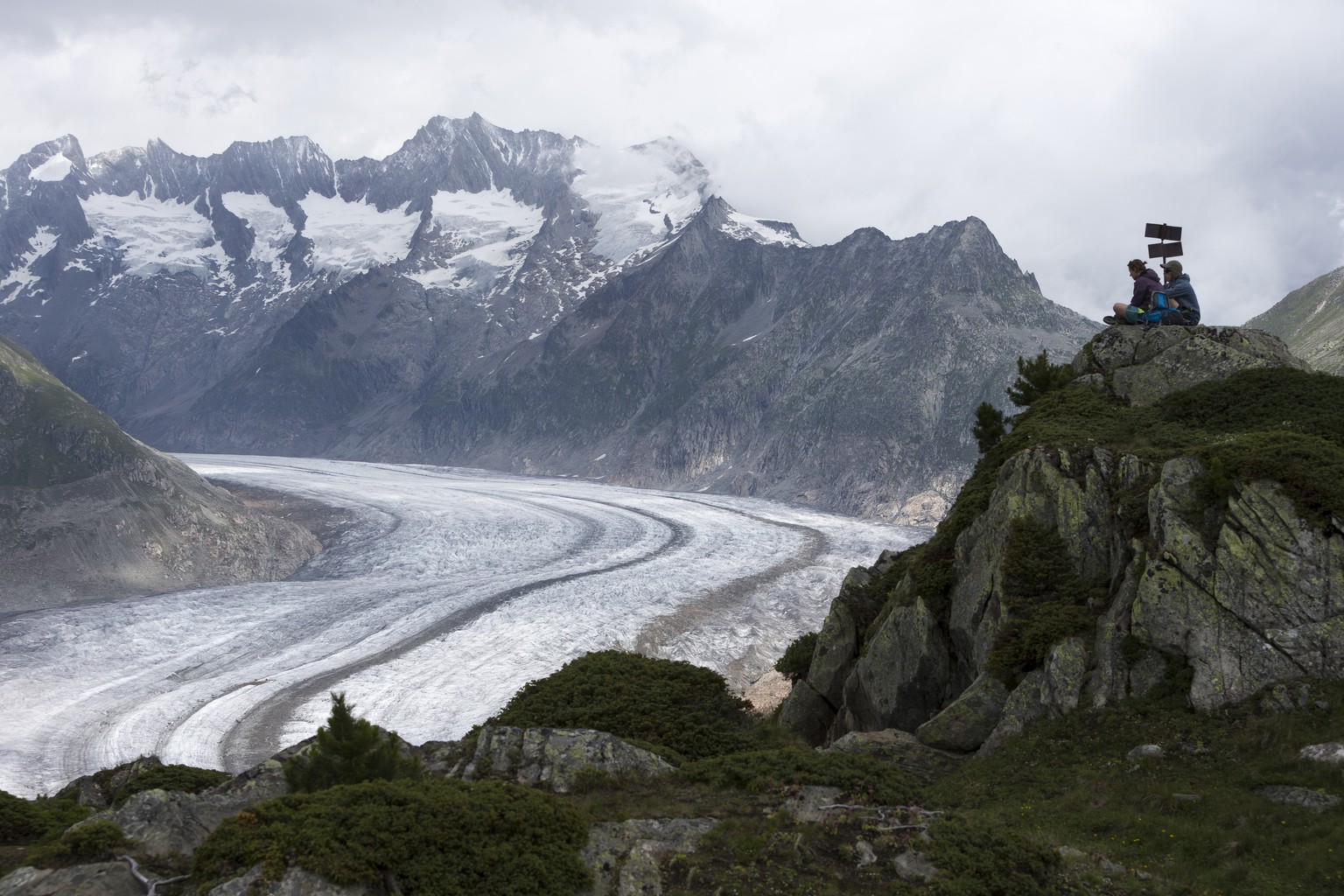 Wanderer halten einen Rast auf einem Felsen mit Blick auf den Aletschgletscher von der Moosfluh aus, auf der Riederalp im Wallis, am Dienstag 11. Juli 2017. (KEYSTONE/Dominic Steinmann)