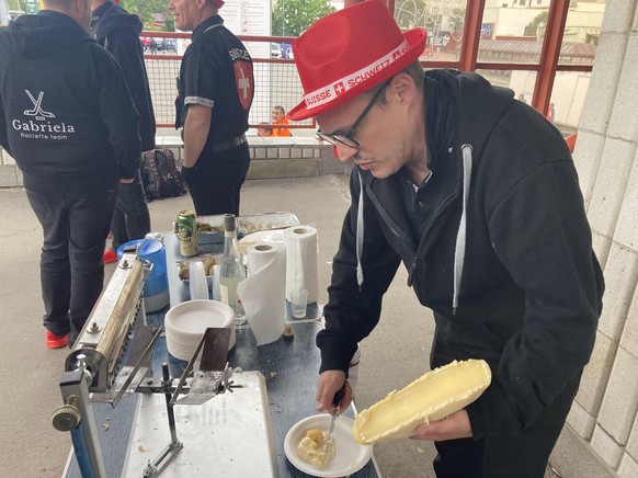 Olivier schabt den Raclette-Käse auf einen Pappteller.