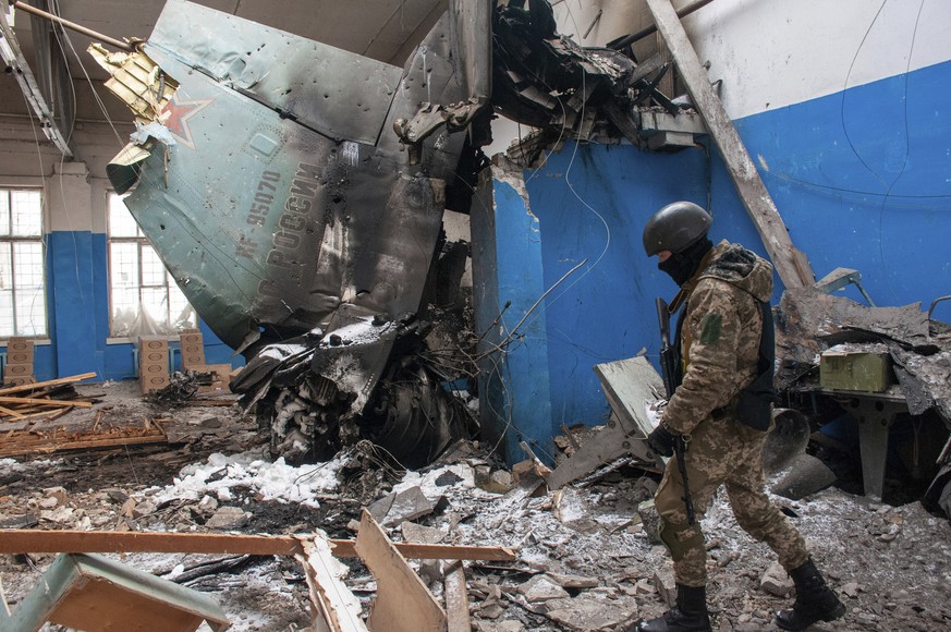 A Ukrainian serviceman walks past the vertical tail fin of a Russian Su-34 bomber lying in a damaged building in Kharkiv, Ukraine, Tuesday, March 8, 2022. (AP Photo/Andrew Marienko)