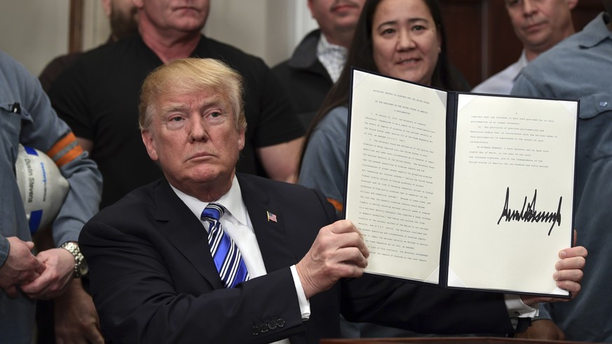 President Donald Trump holds up a proclamation on aluminum during an event in the Roosevelt Room of the White House in Washington, Thursday, March 8, 2018. He also signed one for steel. (AP Photo/Susa ...