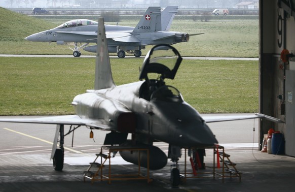 A Swiss F-5 Tiger fighter jet (front) is parked as a F/A-18 fighter jet passes by in the background, at the air base of the Swiss air force in Payerne March 25, 2014. Switzerland will vote on a refere ...