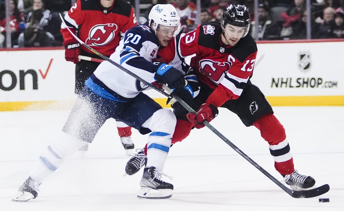 Winnipeg Jets' Karson Kuhlman (20) fights for control of the puck with New Jersey Devils' Nico Hischier (13) during the second period of an NHL hockey game Sunday, Feb. 19, 2023, in Newark,  ...