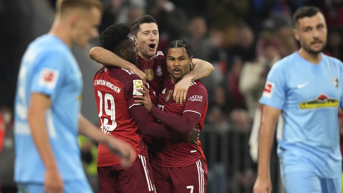 Bayern's Robert Lewandowski, center, celebrates his side's second goal with Bayern's Alphonso Davies, left, and Serge Gnabry during the German Bundesliga soccer match between FC Bayern  ...
