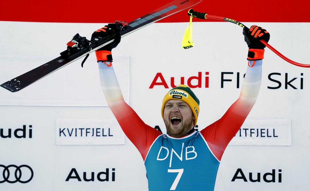 Switzerland's Niels Hintermann celebrates on the podium after winning an alpine ski, men's World Cup downhill race, in Kvitfjell, Norway, Saturday, Feb. 17, 2024. (AP Photo/Alessandro Trovat ...