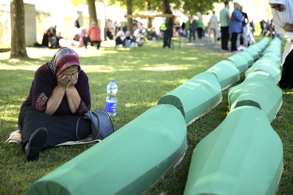 A Bosnian muslim woman mourns next to the coffin containing remains of her family member who is among 50 newly identified victims of Srebrenica Genocide in Potocari, Monday, July 11, 2022. Thousands c ...