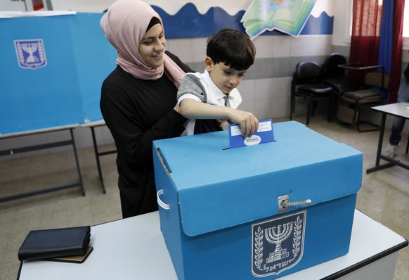 epa07493466 An Israeli Arab citizen from Taiybe town casts her ballot together with her son at a polling station, during the Elections of the 21st Knesset (parliament) of Israel, 09 April 2019. Accord ...