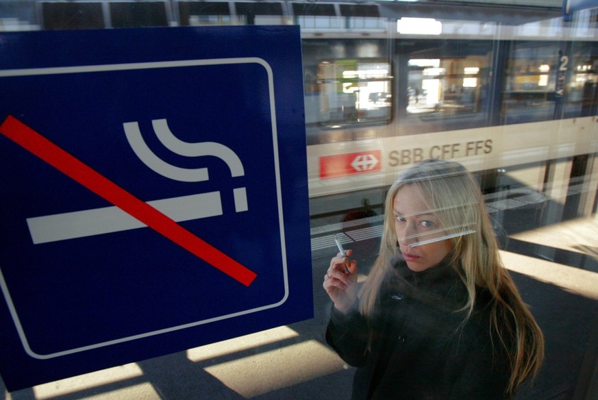 Une jeune femme fume sa cigarette avant de monter dans le train ce dimanche 11 decembre 2005 a Yverdon. Aujourd&#039;hui est le premier jour sans cigarettes dans les trains des CFF, SBB, FFS. (KEYSTON ...
