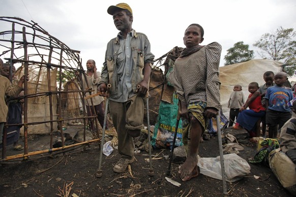 epa03482674 Bashari Kahonbo (L), 72, who lost his left leg during a conflict in 2006, stands next to Sekanabo Jackie (R), 37, who was wounded by a stray bullet during a conflict in 2011, at a roadside ...