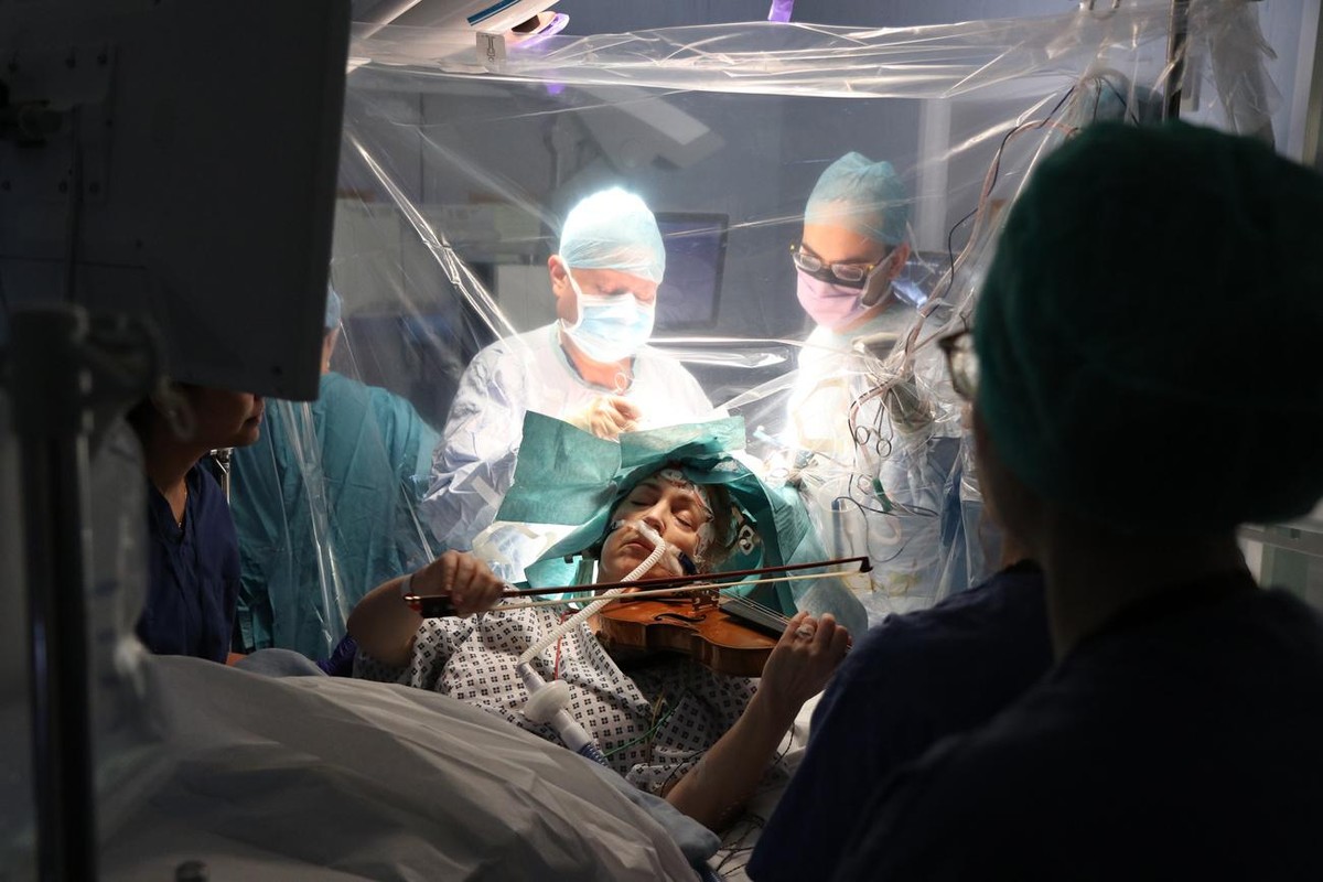 epa08230428 A handout picture provided by the King's College Hospital shows Dagmar Turner playing the violin as doctors perform surgery to remove a brain tumor, at the King's College Hospita ...