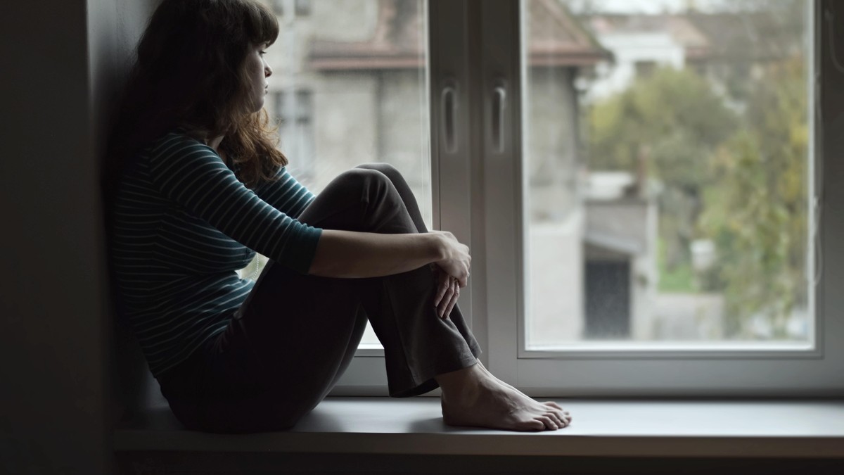 Frau sitzt in Fenster, Quarantäne