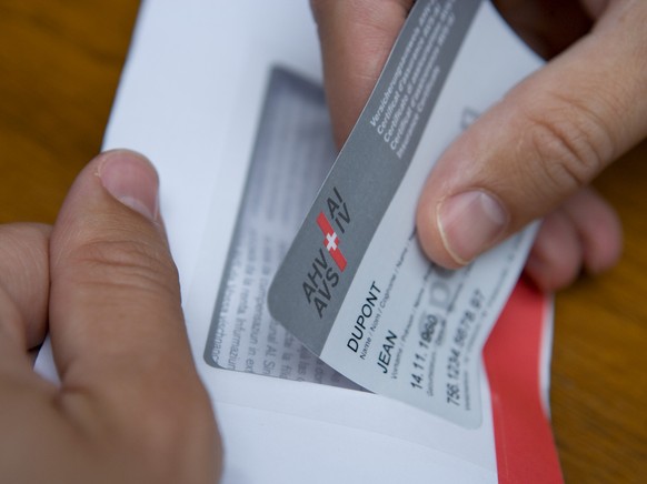 A man takes a prototype of the new insurance certificate of the AHV-IV (AHV: Federal old-age and bereaved people insurance/IV: Disabled people insurance) with the name of the insured party, the date o ...