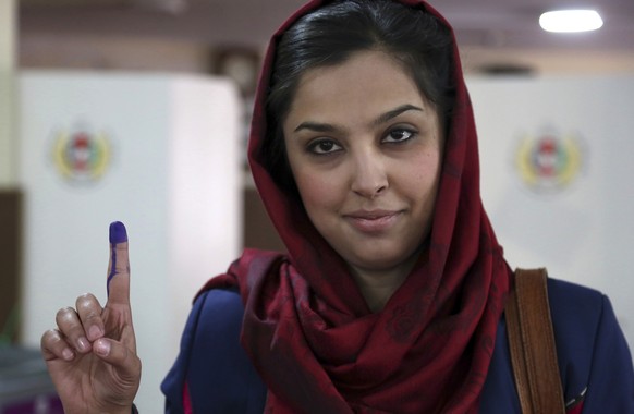 An Afghan woman shows her inked finger after casting her vote at a polling station during the Parliamentary elections in Kabul, Afghanistan, Saturday, Oct. 20, 2018. Tens of thousands of Afghan forces ...