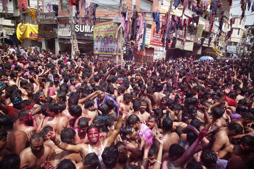 Indians, their faces smeared with color and glitter, dance as water is sprinkled on them during Holi celebrations in Prayagraj, India, Monday, March 29, 2021. Hindus threw colored powder and sprayed w ...