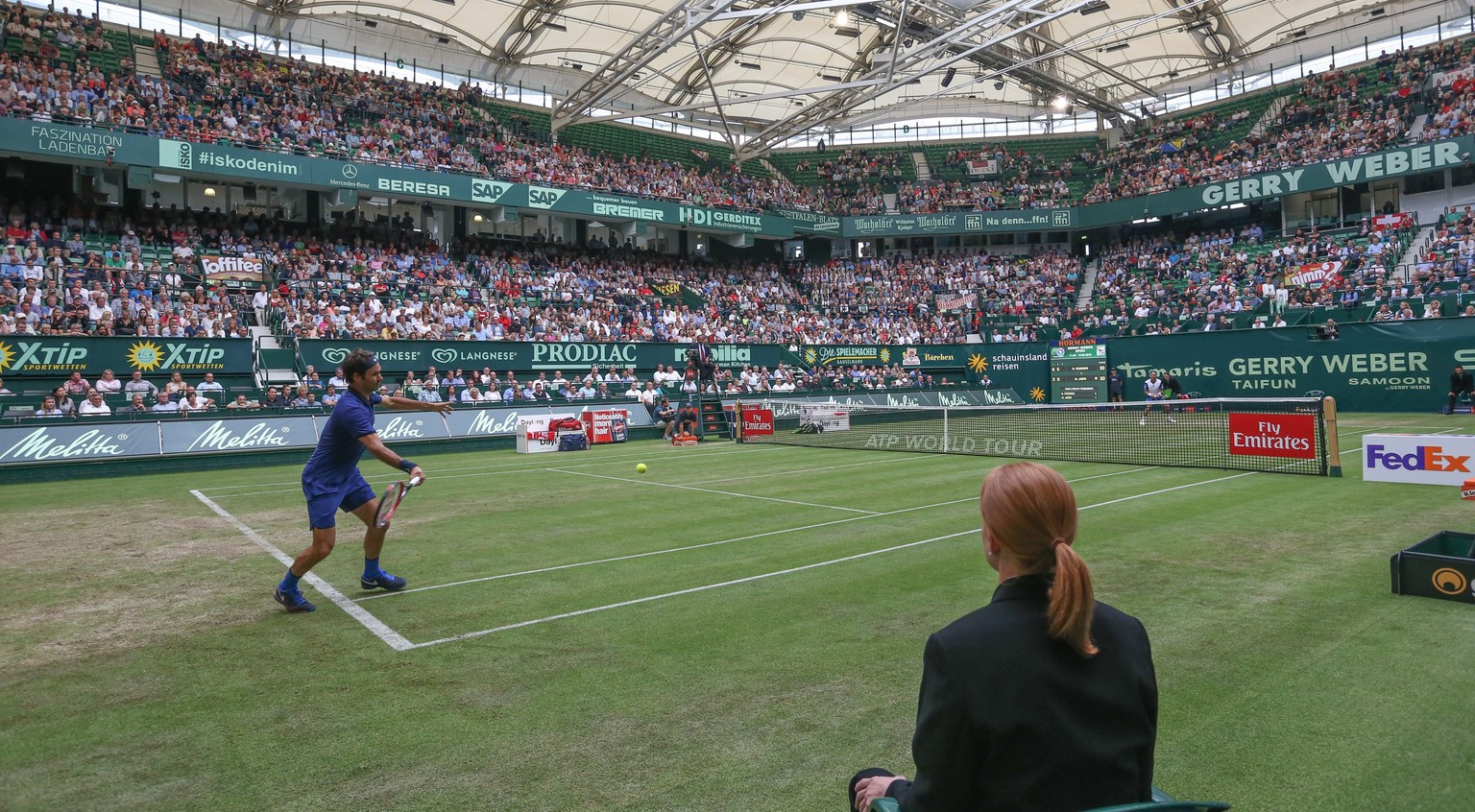 epa05370132 Roger Federer of Switzerland (L) returns a ball to Malek Jaziri of Tunisia (back R) during the ATP tennis tournament in Halle, Germany, 16 June 2016. EPA/FRISO GENTSCH