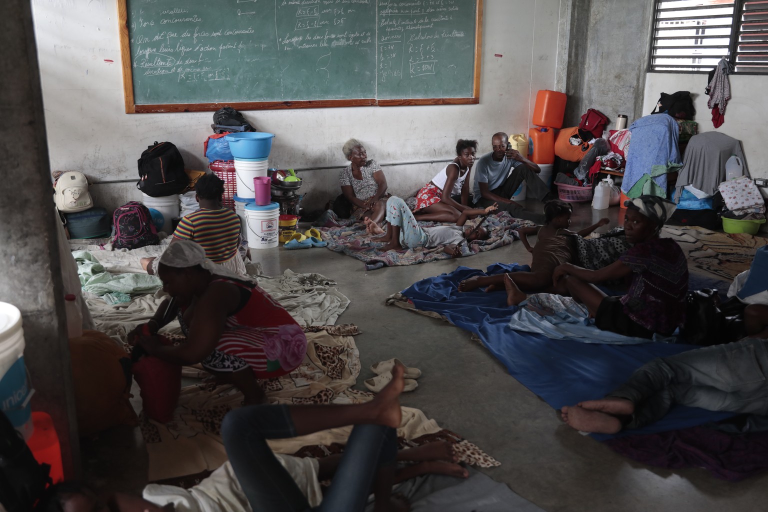 Displaced people sit inside a school where they are taking refuge due to gang violence, as it rains due to Tropical Storm Franklin in Port-au-Prince, Haiti, Wednesday, Aug. 23, 2023. (AP Photo/Odelyn  ...