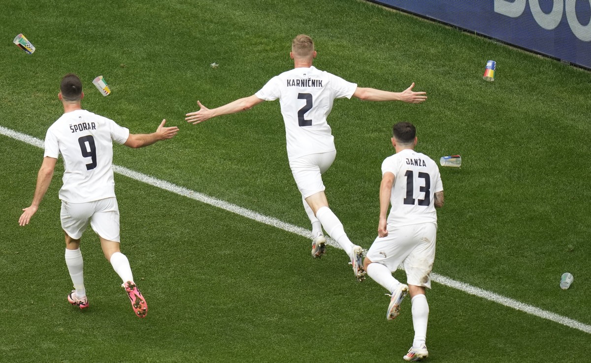 Plastic cups are thrown from the stands at Slovenia's Zan Karnicnik, center, and his teammates celebrating after scoring the opening goal during a Group C match between Slovenia and Serbia at the ...