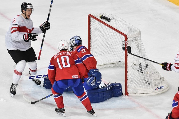 Switzerlandâs Reto Schaeppi, left, scores to 1:0 against Norwayâs Mattias Norstebo, center, and Norwayâs goaltender Henrik Haukeland, right, during their Ice Hockey World Championship group B pr ...