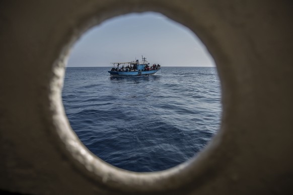 A migrants boat is seen though a porthole before being rescued by the Open Arms aid boat on Sunday June 30, 2019. A Spanish humanitarian group says its rescue ship spotted 40 dehydrated migrants at se ...