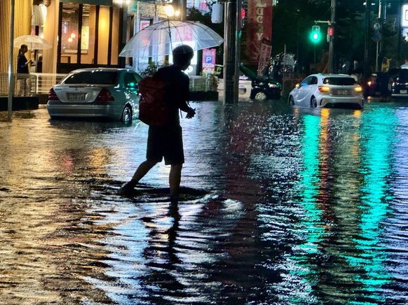 epa13166806 A man walks in a flooded road following heavy rain in Ichikawa, Chiba prefecture, near Tokyo, Japan, 13 August 2026. Southern Kanto was hit by localized torrential rain and the Japan Meteo ...