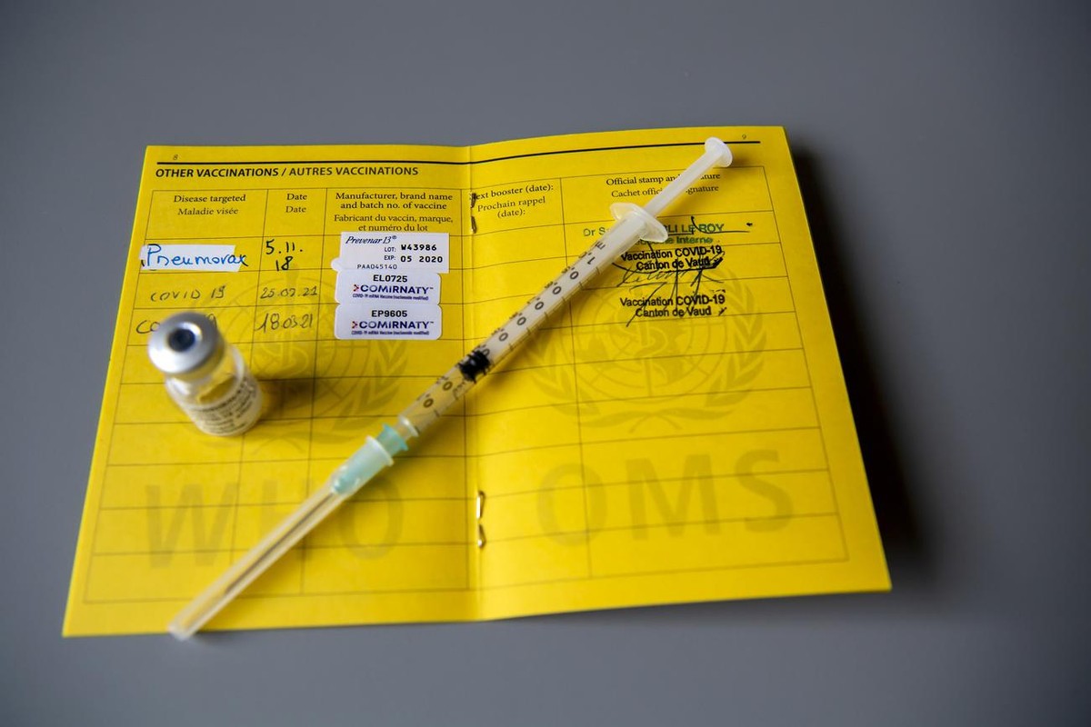 CERTIFICAT COVID Une fiole du vaccin Pfizer-BioNTech et une seringue sont photographiees sur un carnet de l'OMS de certificat international de vaccination ou de prophylaxie, faudra-t-il un jour u ...