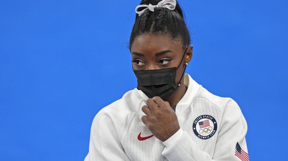 Simone Biles, of the United States, stands wearing a mask after she exited the team final with apparent injury, at the 2020 Summer Olympics, Tuesday, July 27, 2021, in Tokyo. The 24-year-old reigning  ...