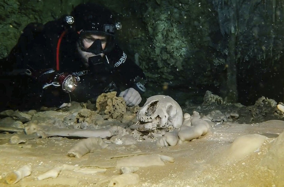 This undated photo released by Mexico's National Anthropology and History Institute (INAH) shows a diver from the Great Mayan Aquifer project looking at human remains believed to be from the Plei ...