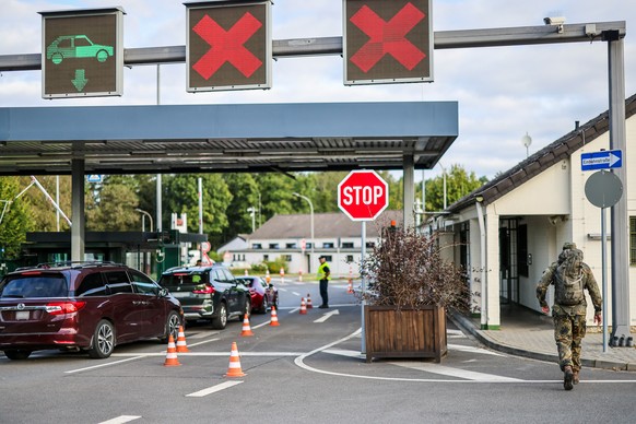 23.08.2024, Nordrhein-Westfalen, Geilenkirchen: Am Morgen kontrollieren Soldaten die Einfahrt in die Nato Air Base, ein Soldat in Tarnkleidung ist zu Fu